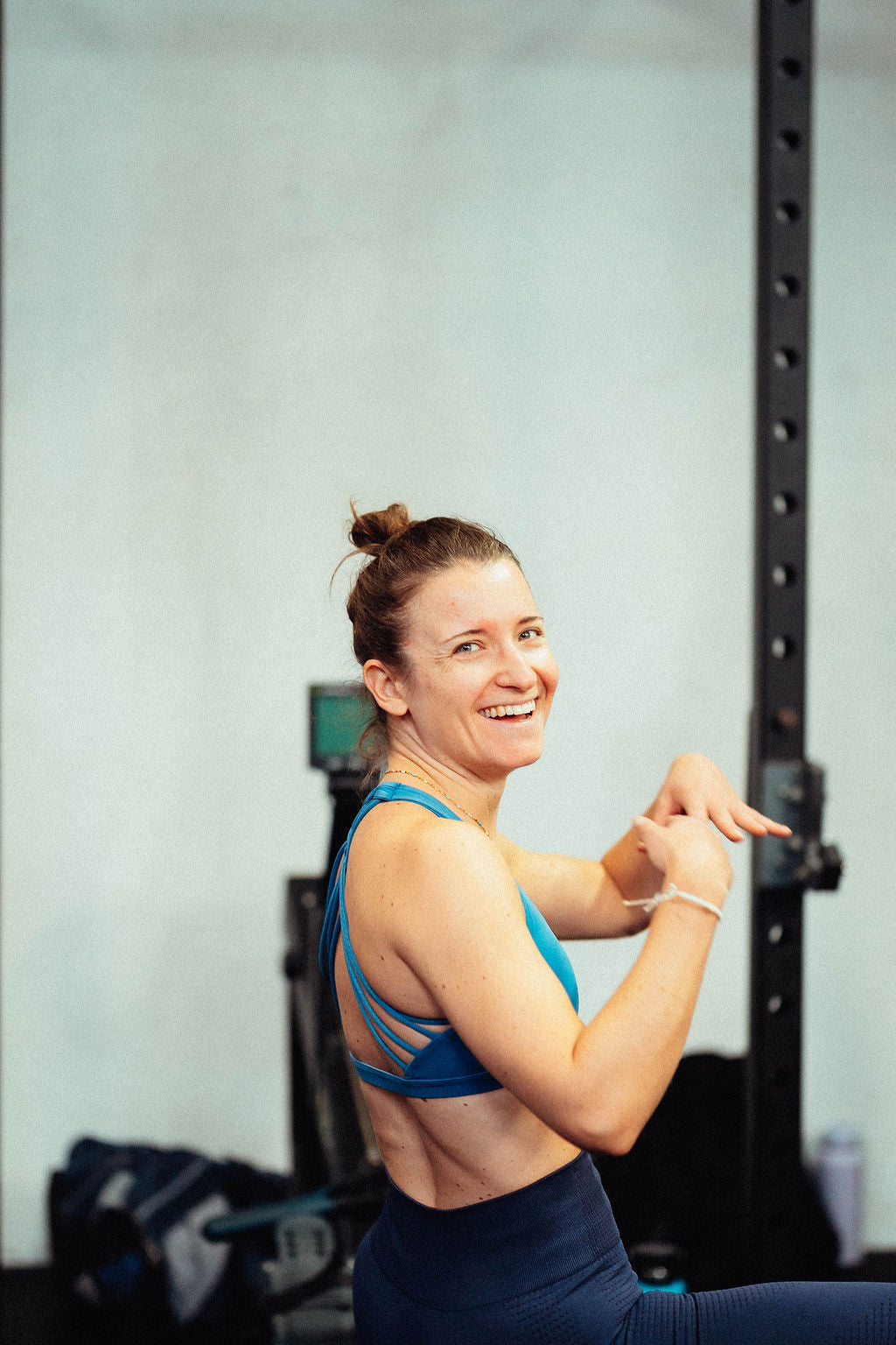Happy woman in athletic wear in a gym setting, stretching after a successful training session