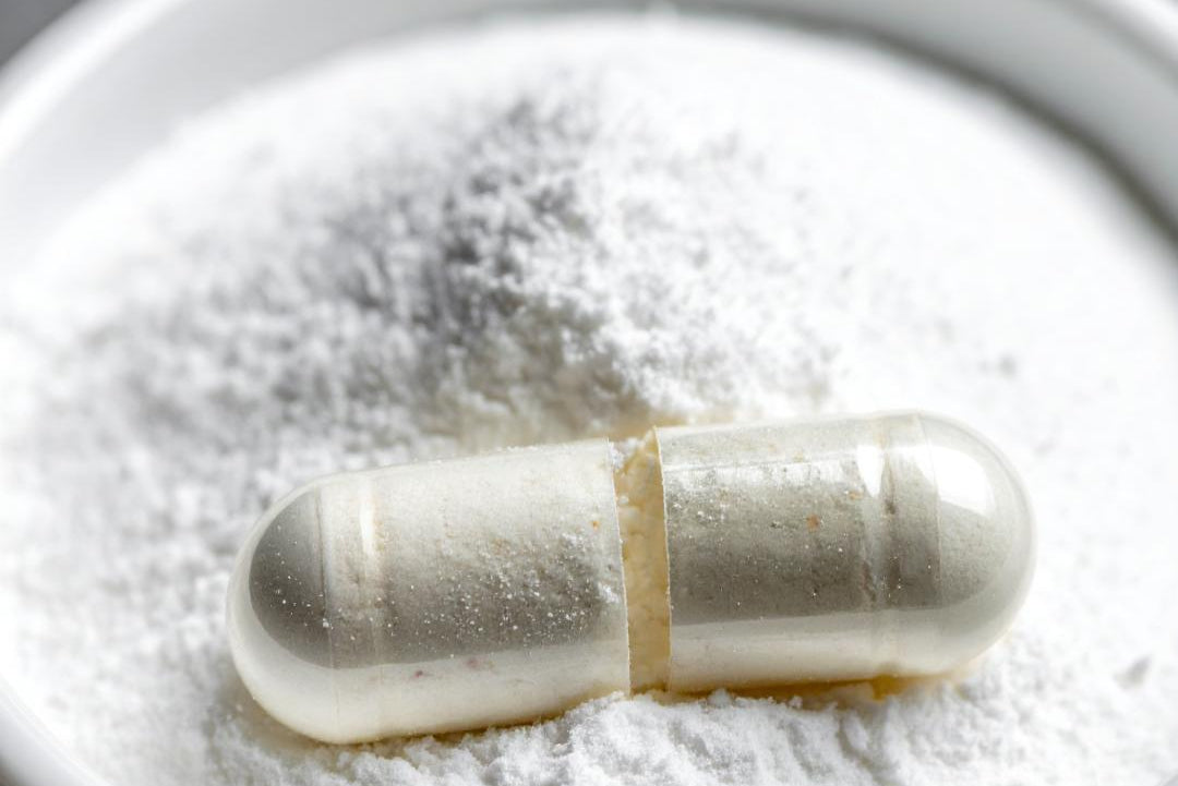 Capsule on a white powdery background, representing the B Vitamins added to the Move Blend Supplement